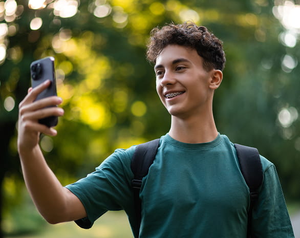 smiling teen taking a picture of something with their phone