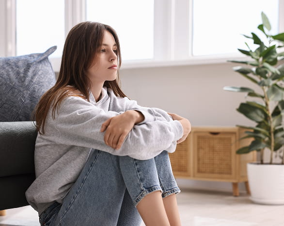 Signs of Trauma - girl sitting on the floor, arms hugging her knees, going through potential trauma