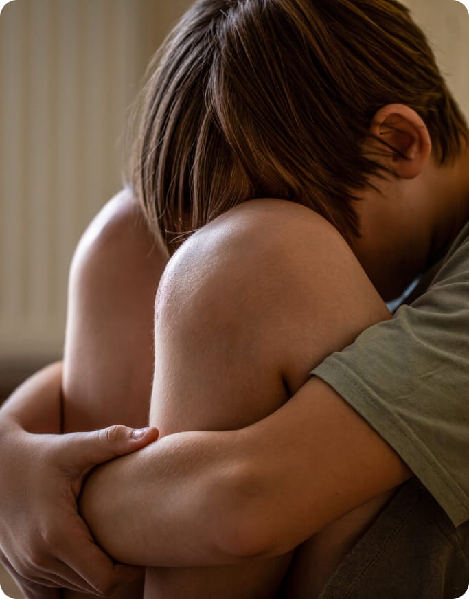 a boy with his face buried in his knees, obviously going through something distressing.