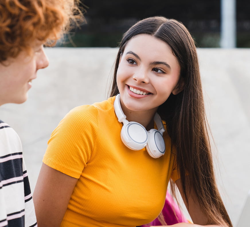 2 teens discussing something, smiling