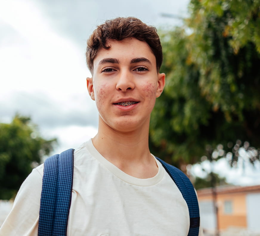 a teenager smiling at the camera with his backpack on